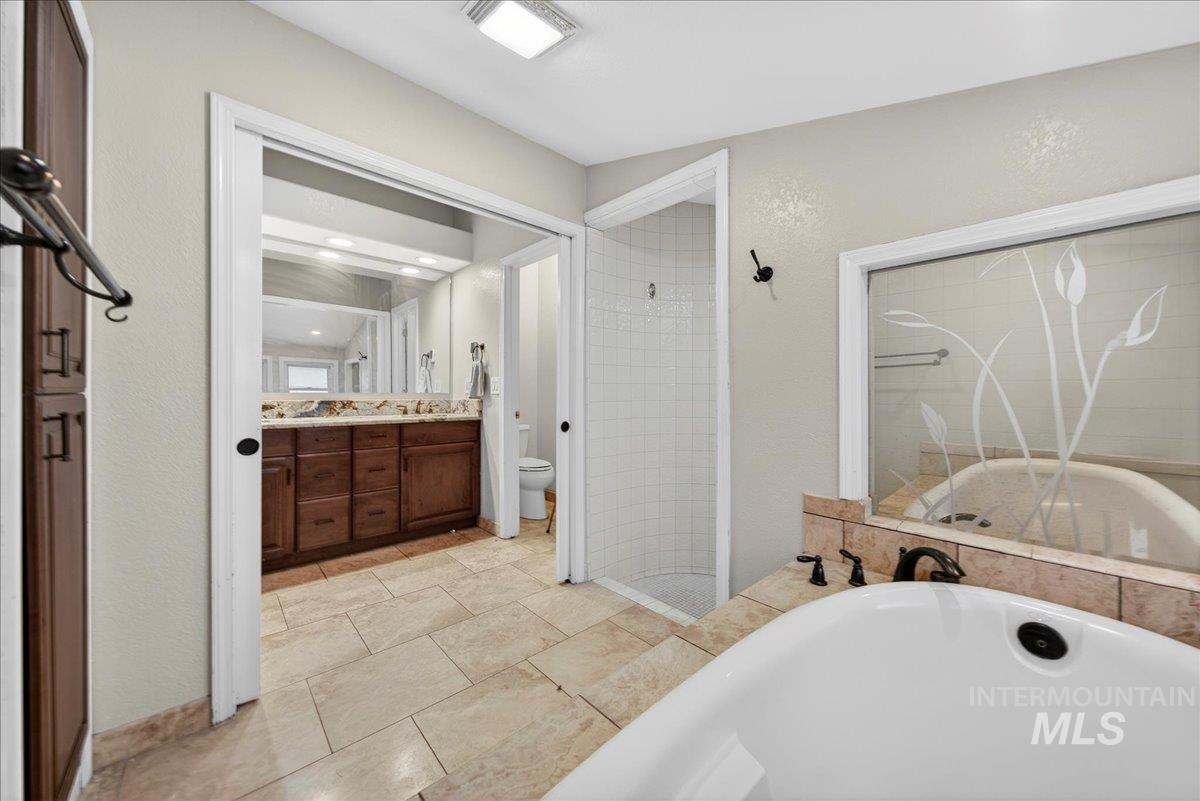 Full bathroom with vanity, a bathtub, a shower stall, and a textured wall