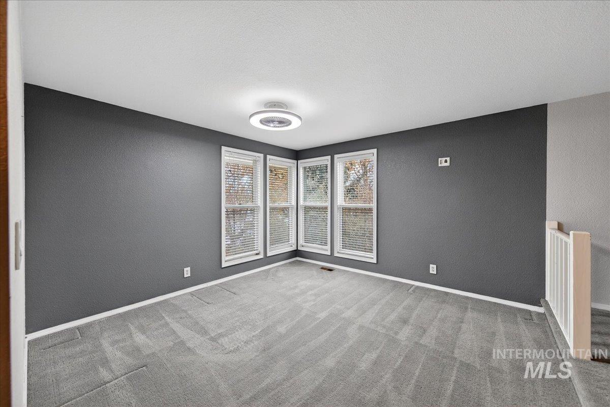 Spare room with a textured wall, carpet, and a textured ceiling