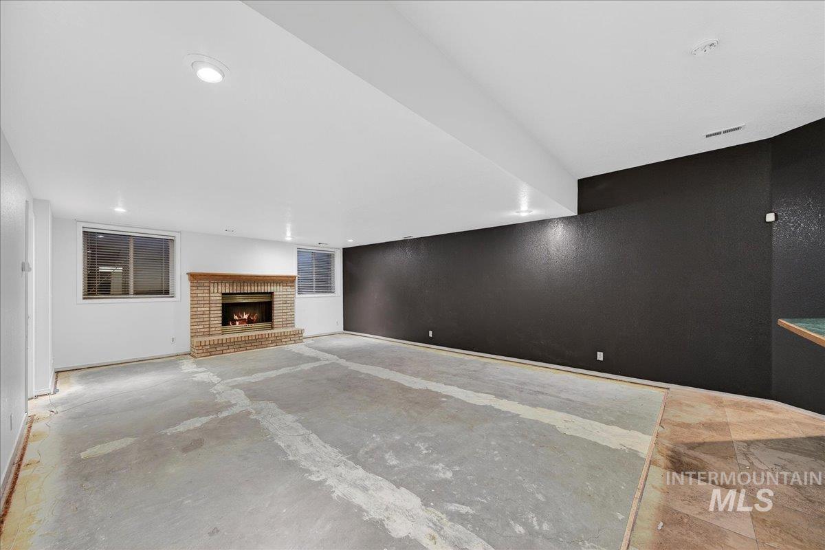 Unfurnished living room with a fireplace and unfinished concrete flooring