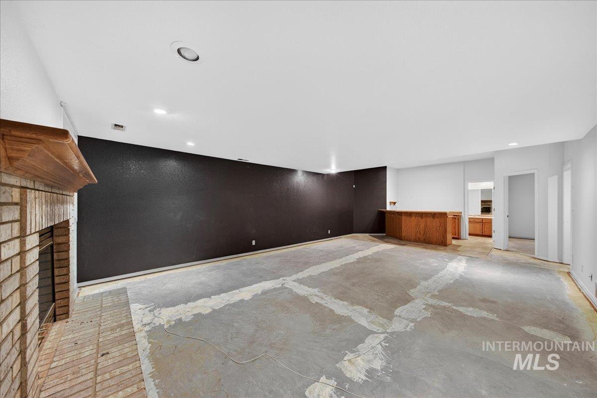 Unfurnished living room with unfinished concrete floors and a brick fireplace