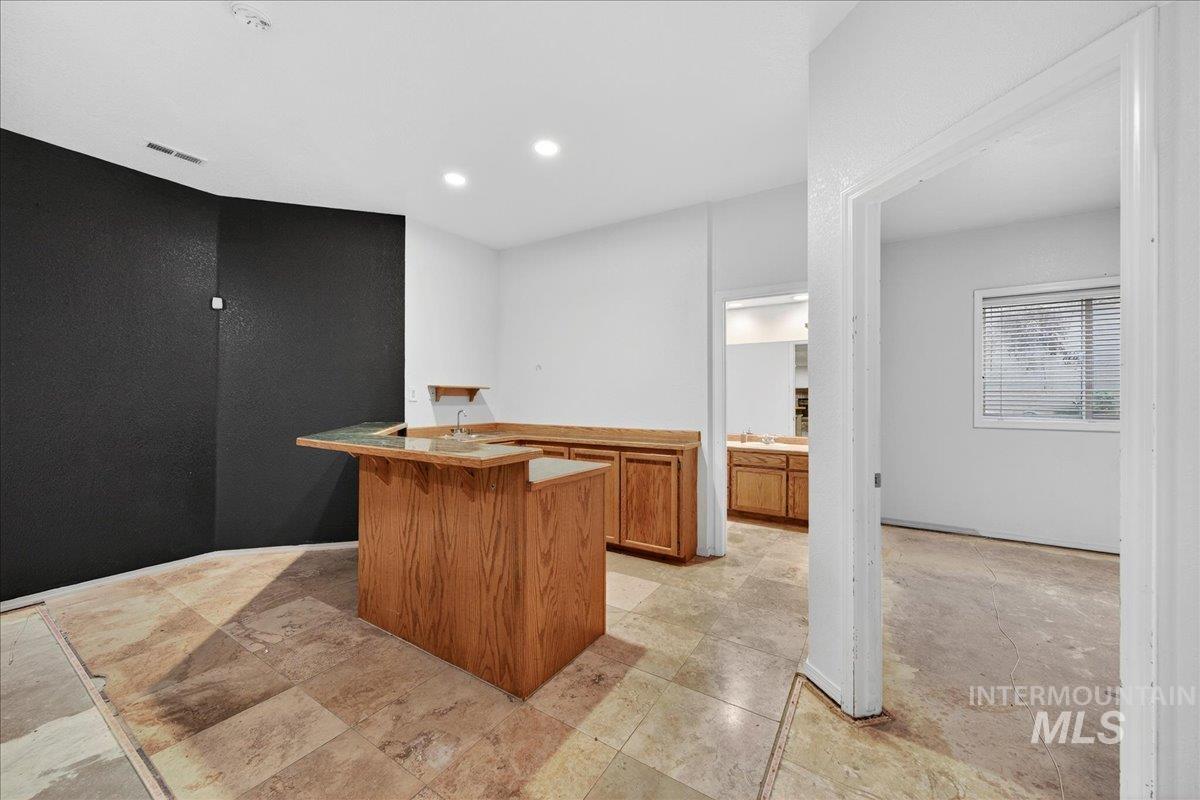 Bar featuring brown cabinetry, light countertops, and recessed lighting