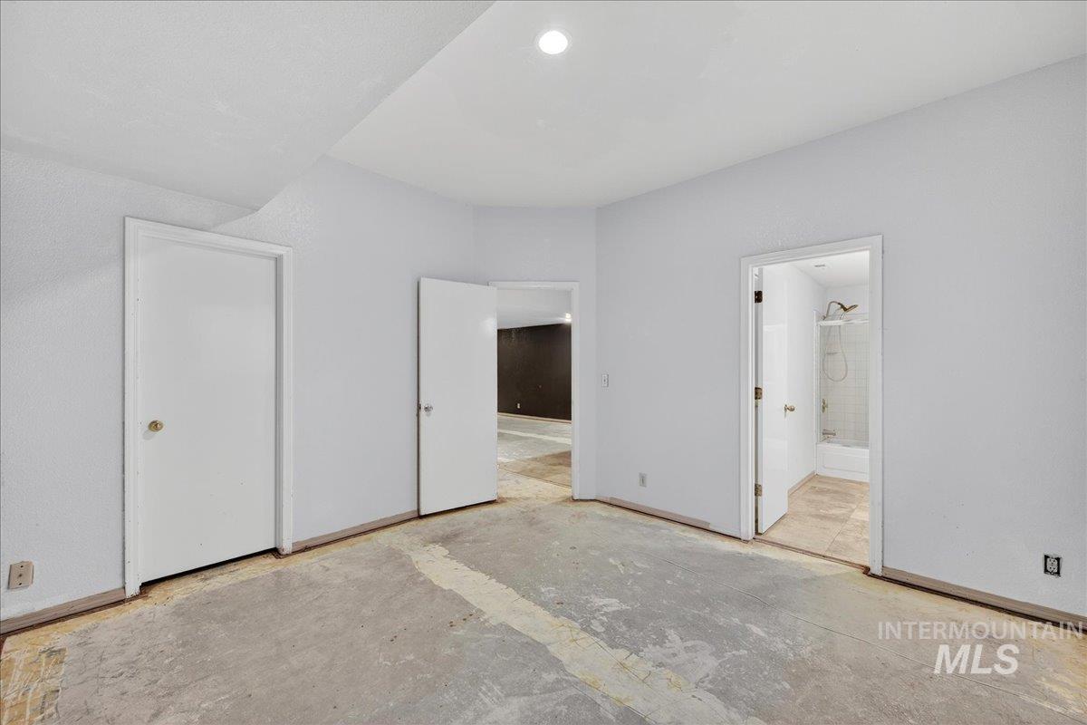 Unfurnished bedroom featuring ensuite bath and concrete flooring