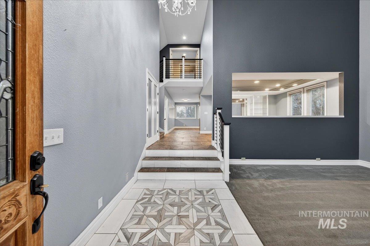 Foyer entrance featuring light tile patterned floors, a towering ceiling, inlaid floor details, light carpet, and recessed lighting