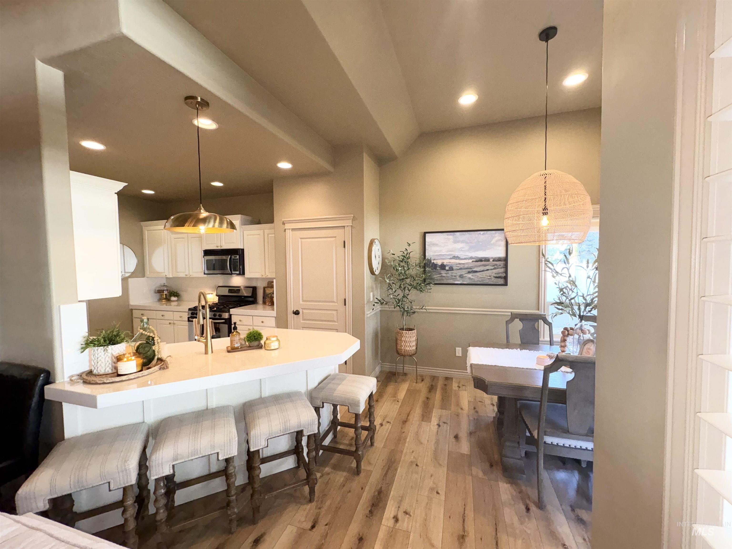 Kitchen with white cabinetry, light countertops, a kitchen bar, appliances with stainless steel finishes, and recessed lighting