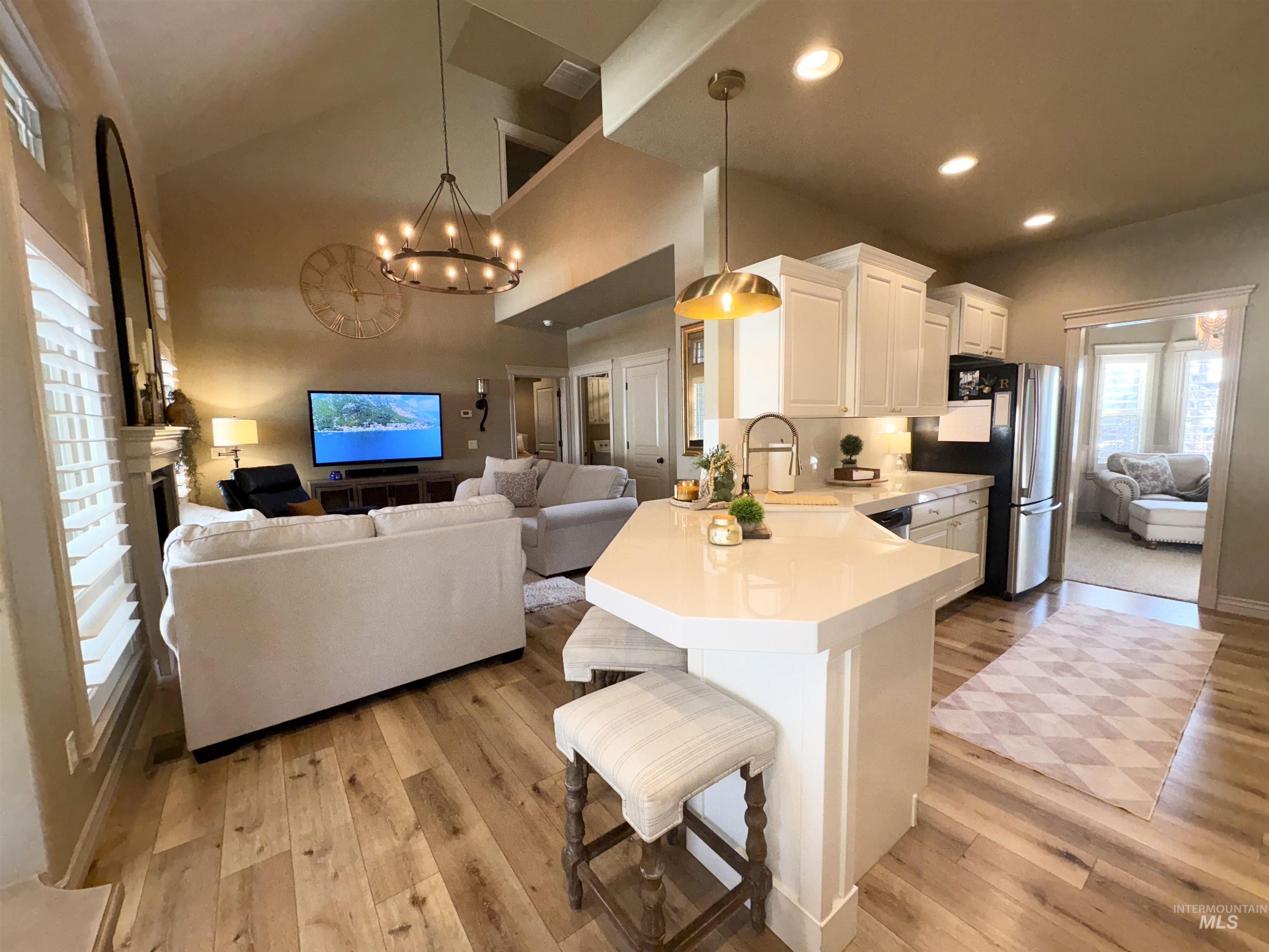 Kitchen featuring open floor plan, a kitchen bar, a peninsula, light countertops, and hanging light fixtures
