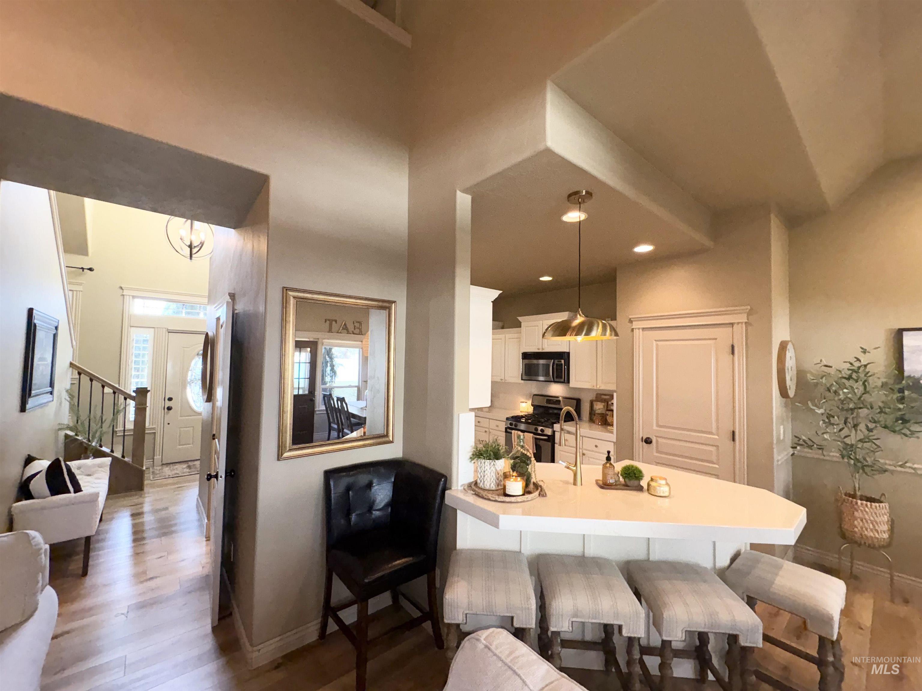 Kitchen with a kitchen bar, dark wood-style flooring, white cabinetry, light countertops, and appliances with stainless steel finishes