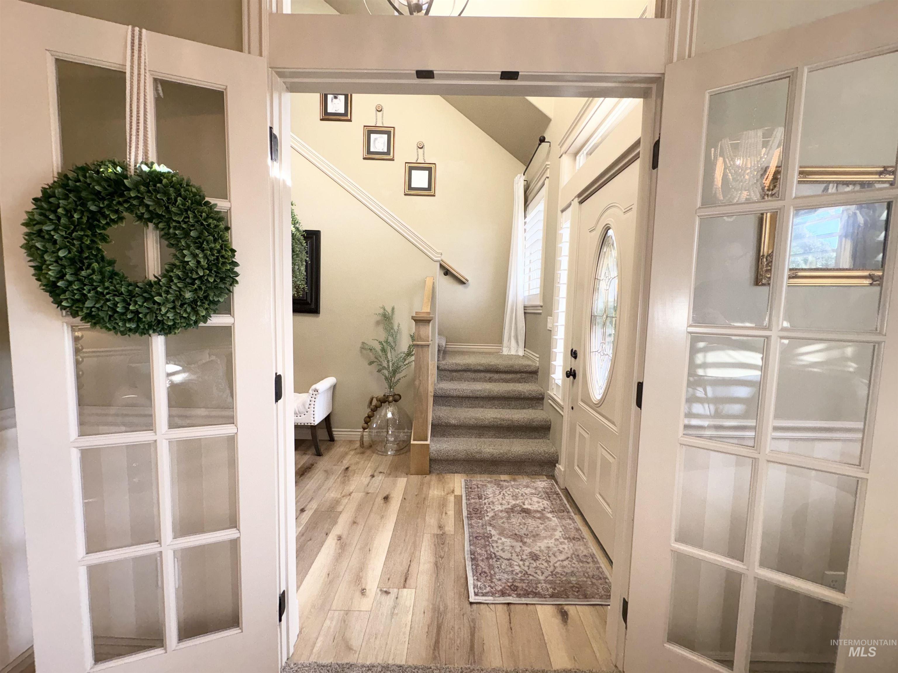 Entryway with light wood-style floors, stairway, and vaulted ceiling