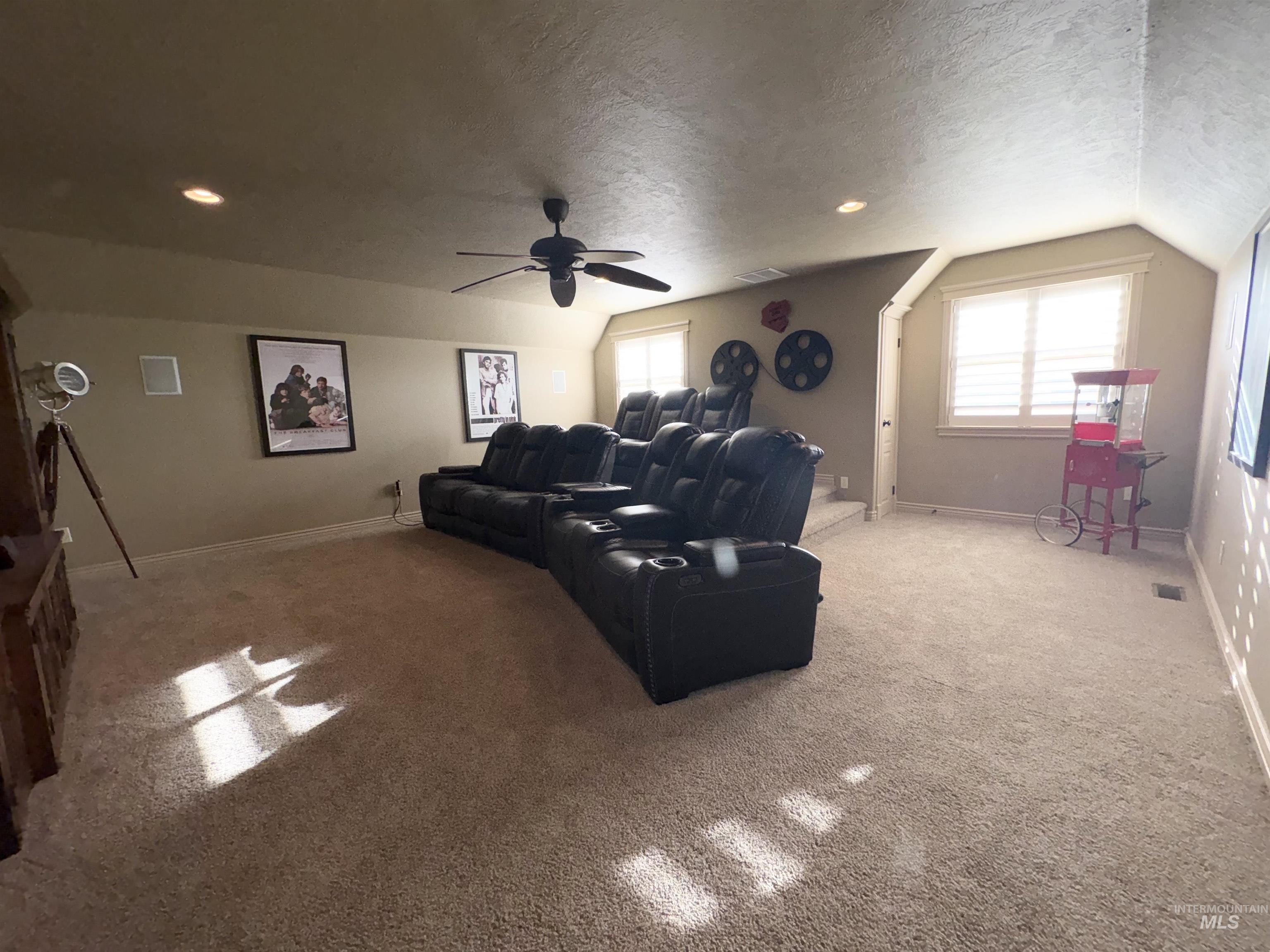 Home theater room with a textured ceiling, light carpet, vaulted ceiling, a ceiling fan, and recessed lighting
