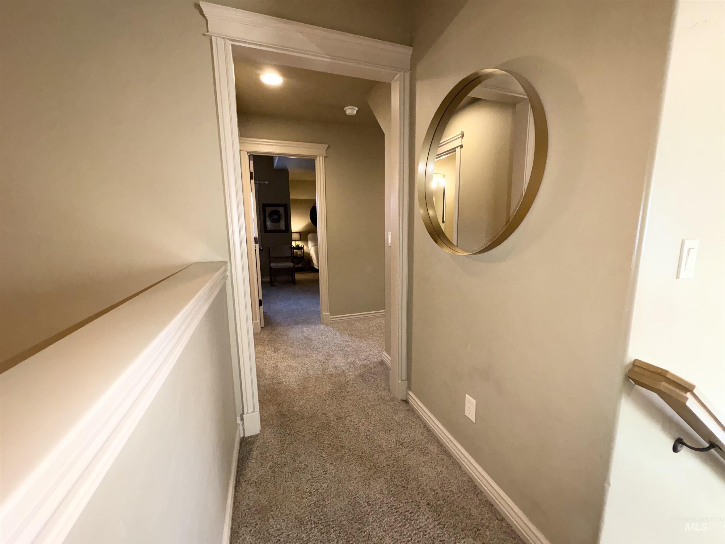 Corridor featuring dark carpet and baseboards