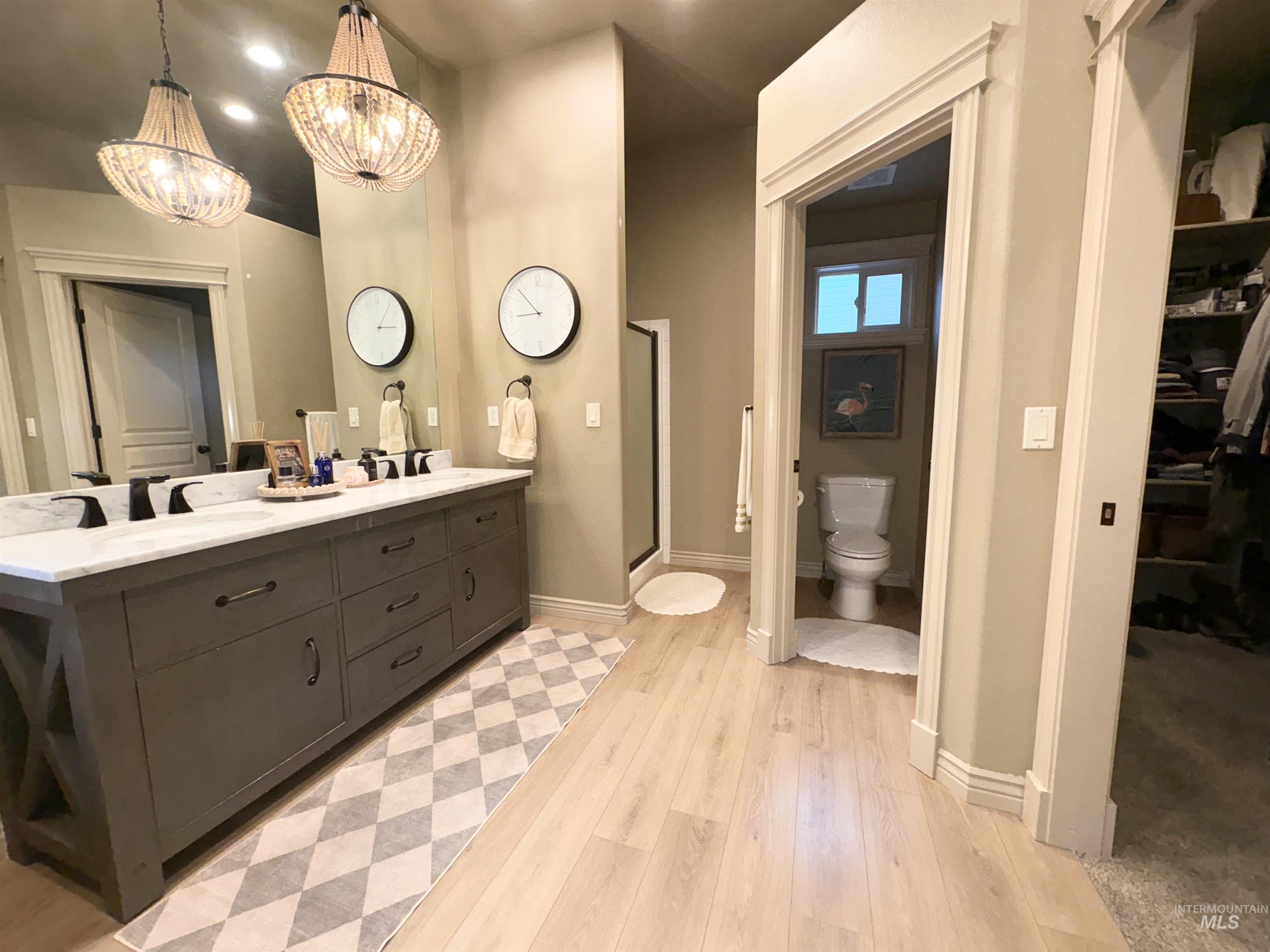 Full bath featuring a spacious closet, double vanity, recessed lighting, light wood finished floors, and a shower stall