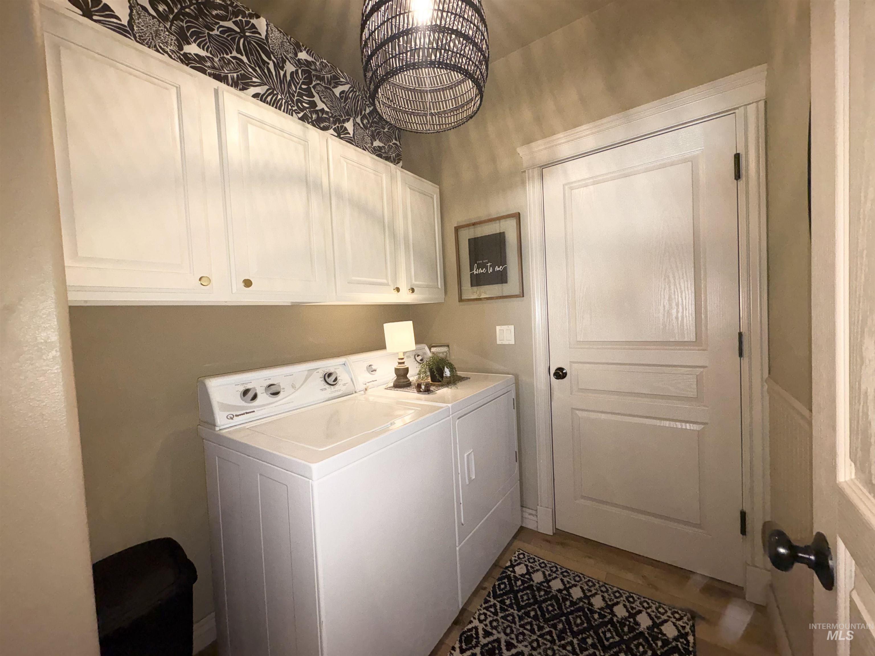 Laundry room featuring a chandelier, washing machine and dryer, and cabinet space