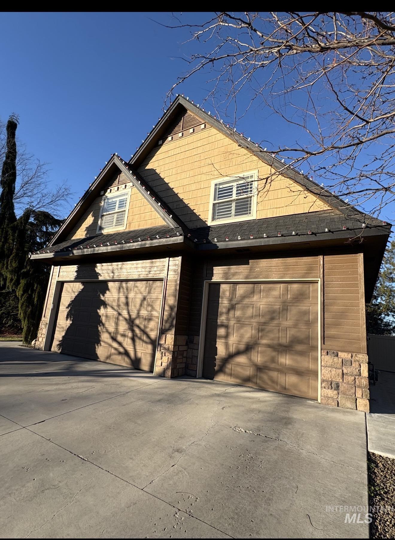 View of front of house featuring stone siding, a garage, and driveway