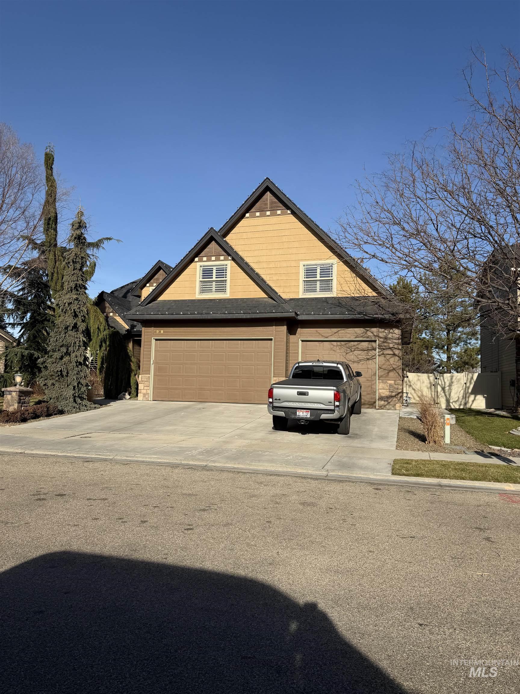 View of front facade with a garage, driveway, and stone siding