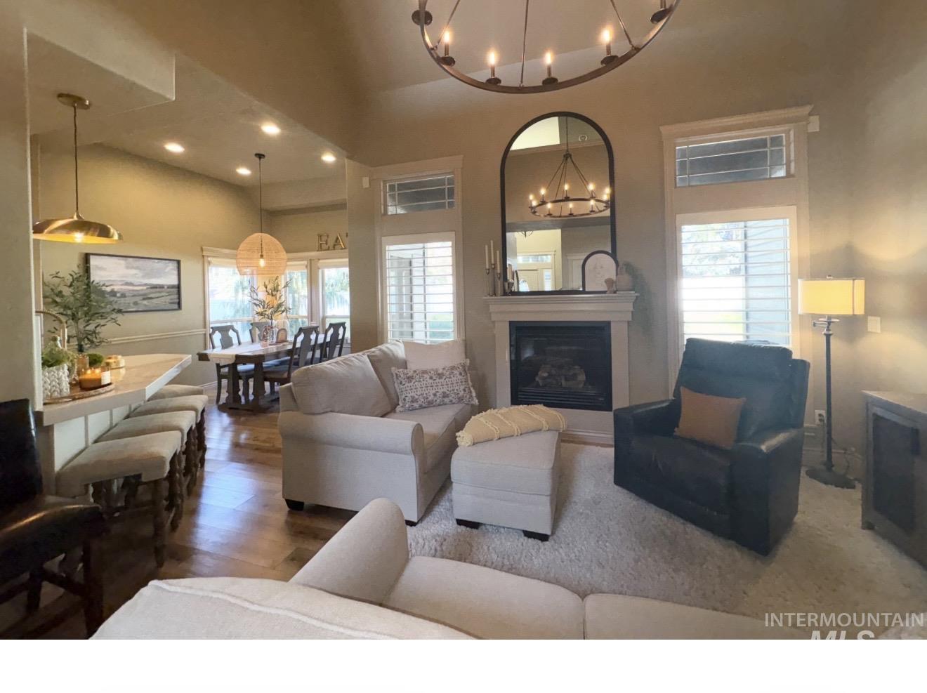 Living area featuring a glass covered fireplace, wood finished floors, recessed lighting, plenty of natural light, and a chandelier