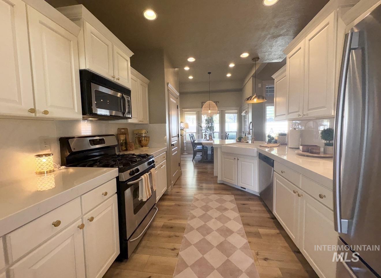 Kitchen featuring appliances with stainless steel finishes, pendant lighting, recessed lighting, white cabinets, and light wood-style floors