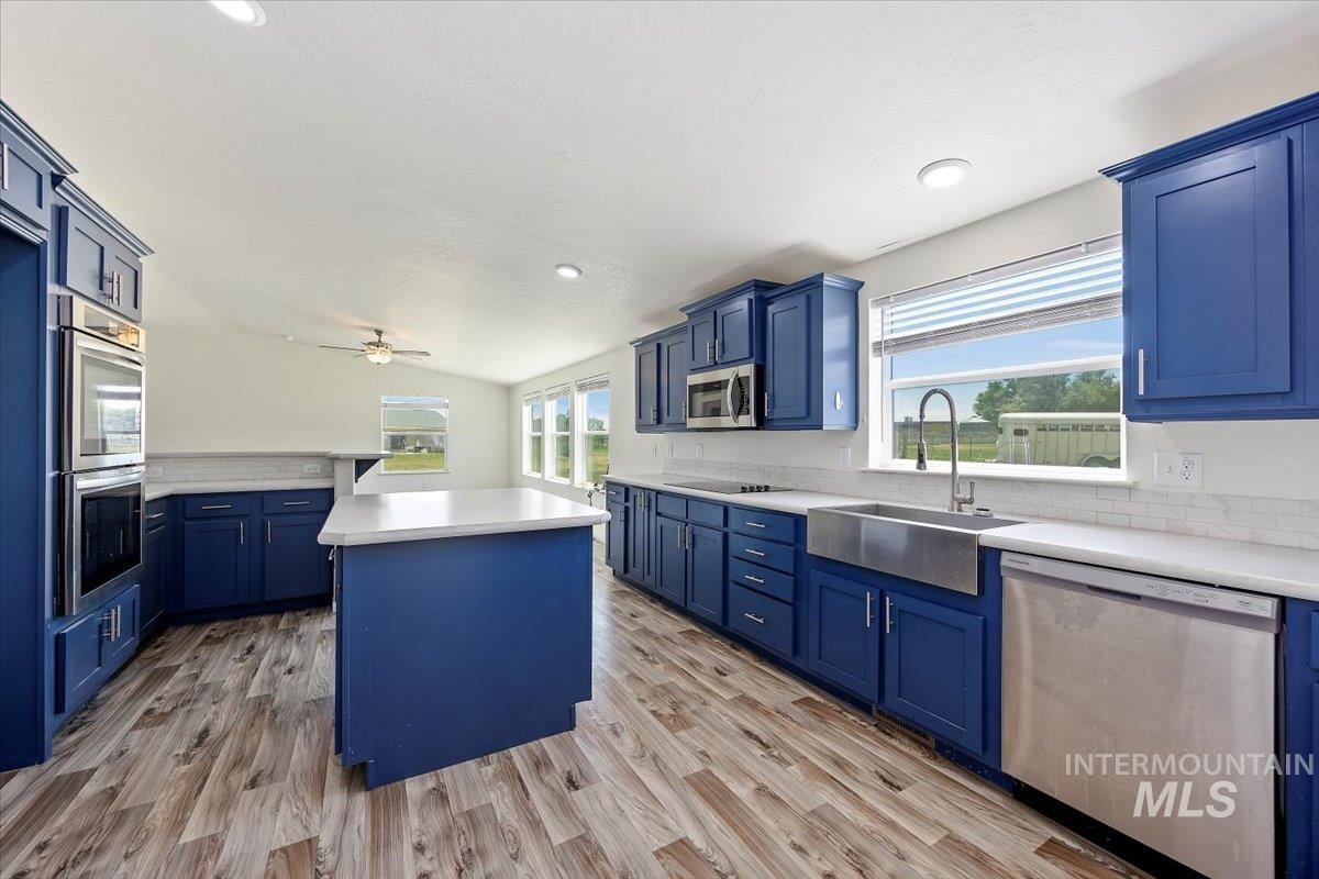 Kitchen featuring blue cabinets, a kitchen island, appliances with stainless steel finishes, light wood-type flooring, and recessed lighting