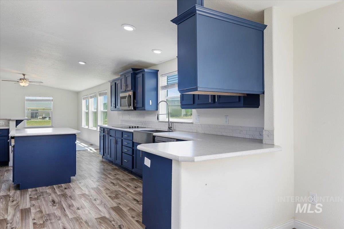 Kitchen featuring blue cabinetry, light countertops, a peninsula, ceiling fan, and recessed lighting