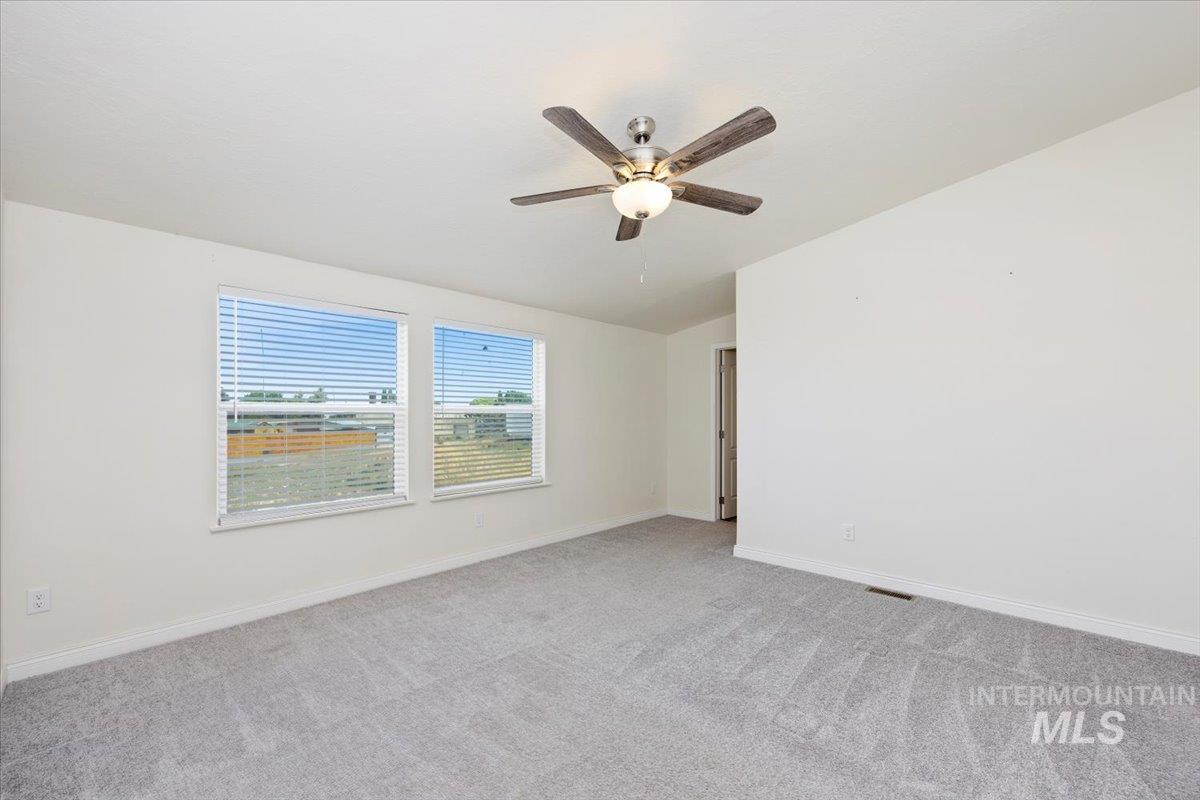 Unfurnished room with light colored carpet, lofted ceiling, and a ceiling fan