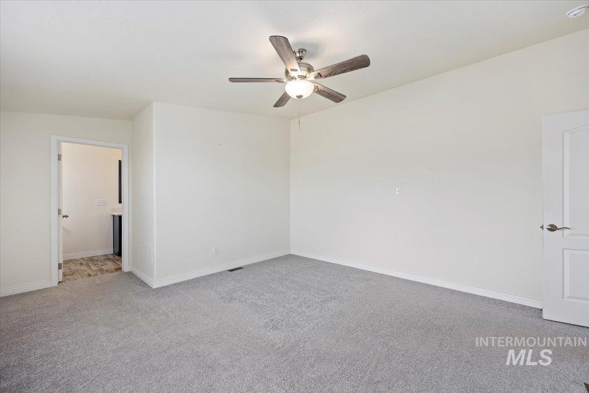 Spare room with light carpet and a ceiling fan