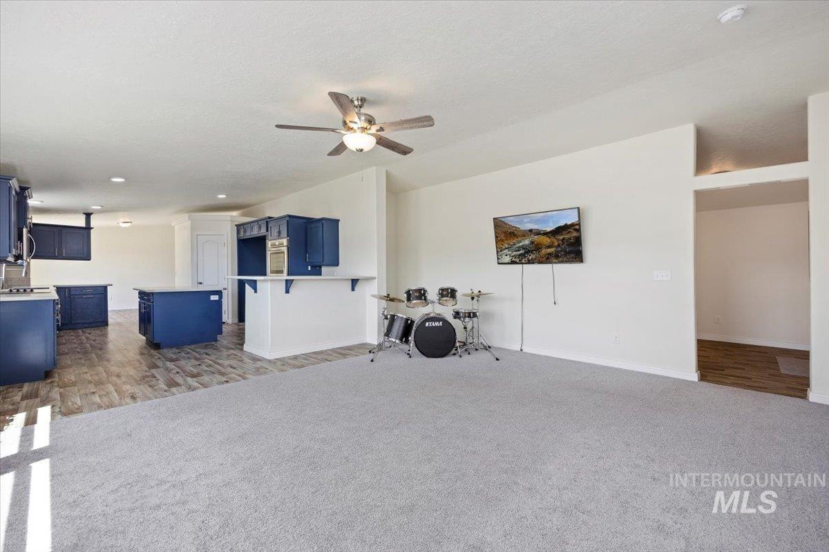 Living area with a ceiling fan, dark carpet, recessed lighting, and dark wood-type flooring