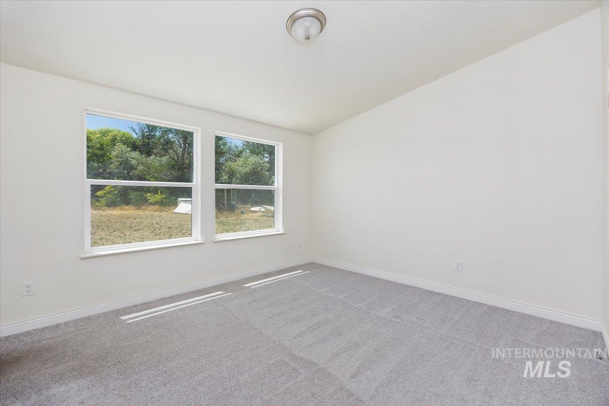 Carpeted empty room with lofted ceiling and baseboards
