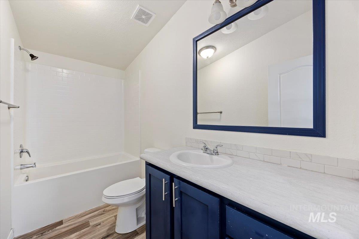 Bathroom featuring tub / shower combination, vanity, and light wood-type flooring