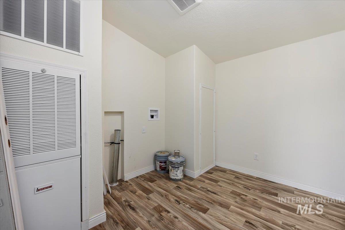 Washroom featuring a heating unit, hookup for a washing machine, wood finished floors, and lofted ceiling