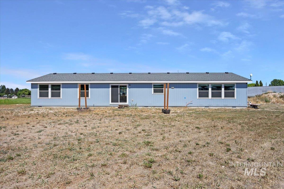 Back of house with roof with shingles and a lawn
