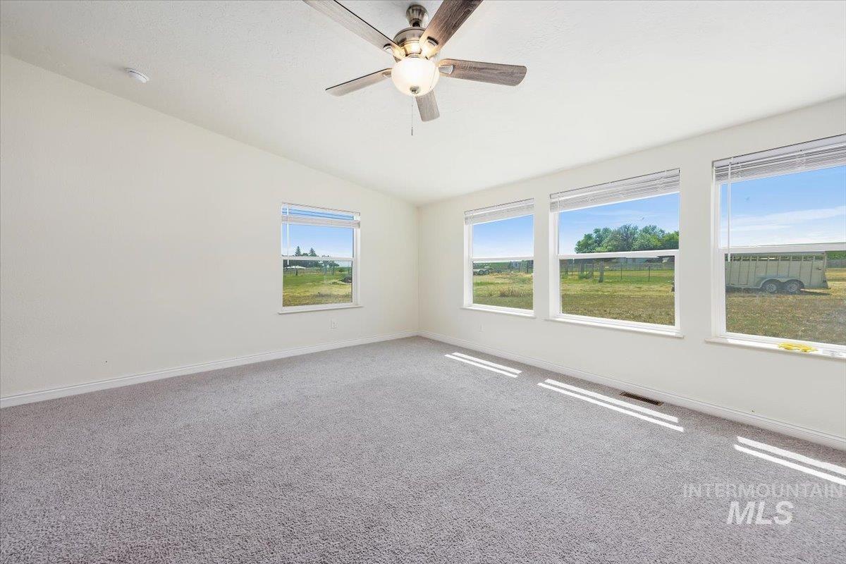 Empty room with vaulted ceiling, carpet flooring, and ceiling fan