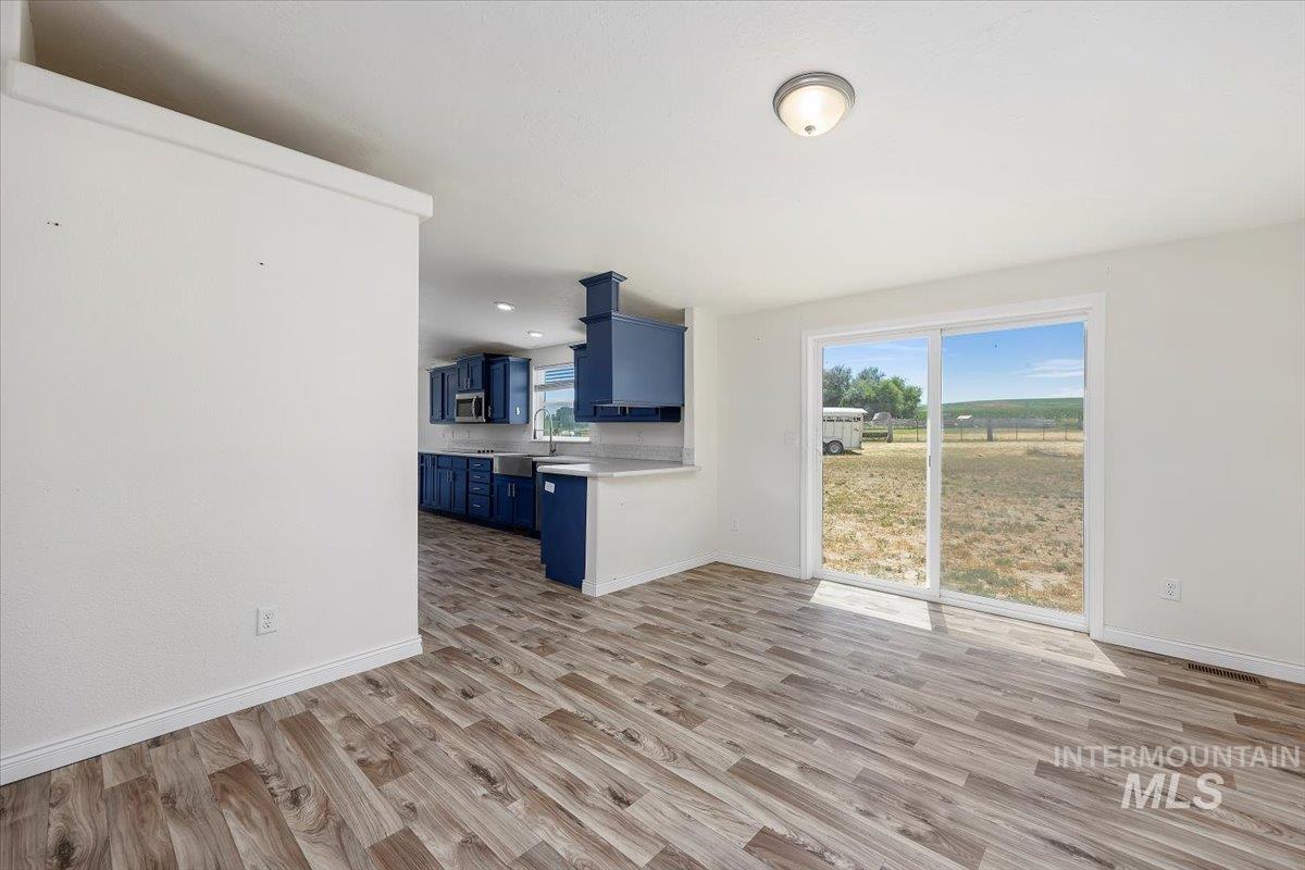 Kitchen featuring blue cabinetry, light wood-type flooring, light countertops, and stainless steel microwave