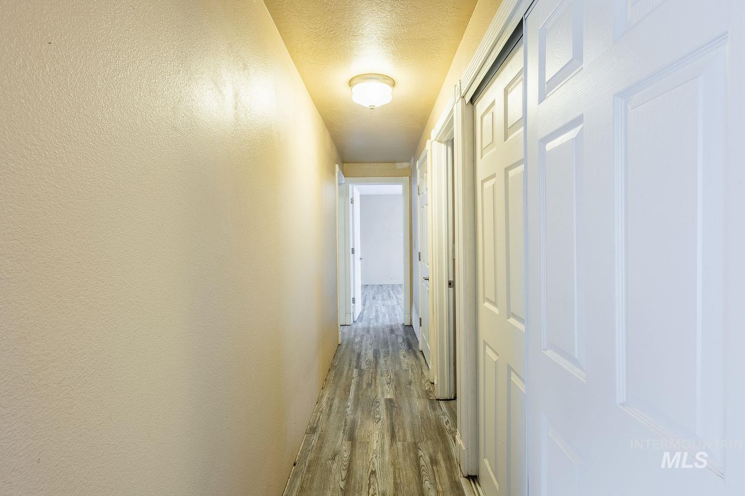 Hall with light wood-style flooring and a textured ceiling