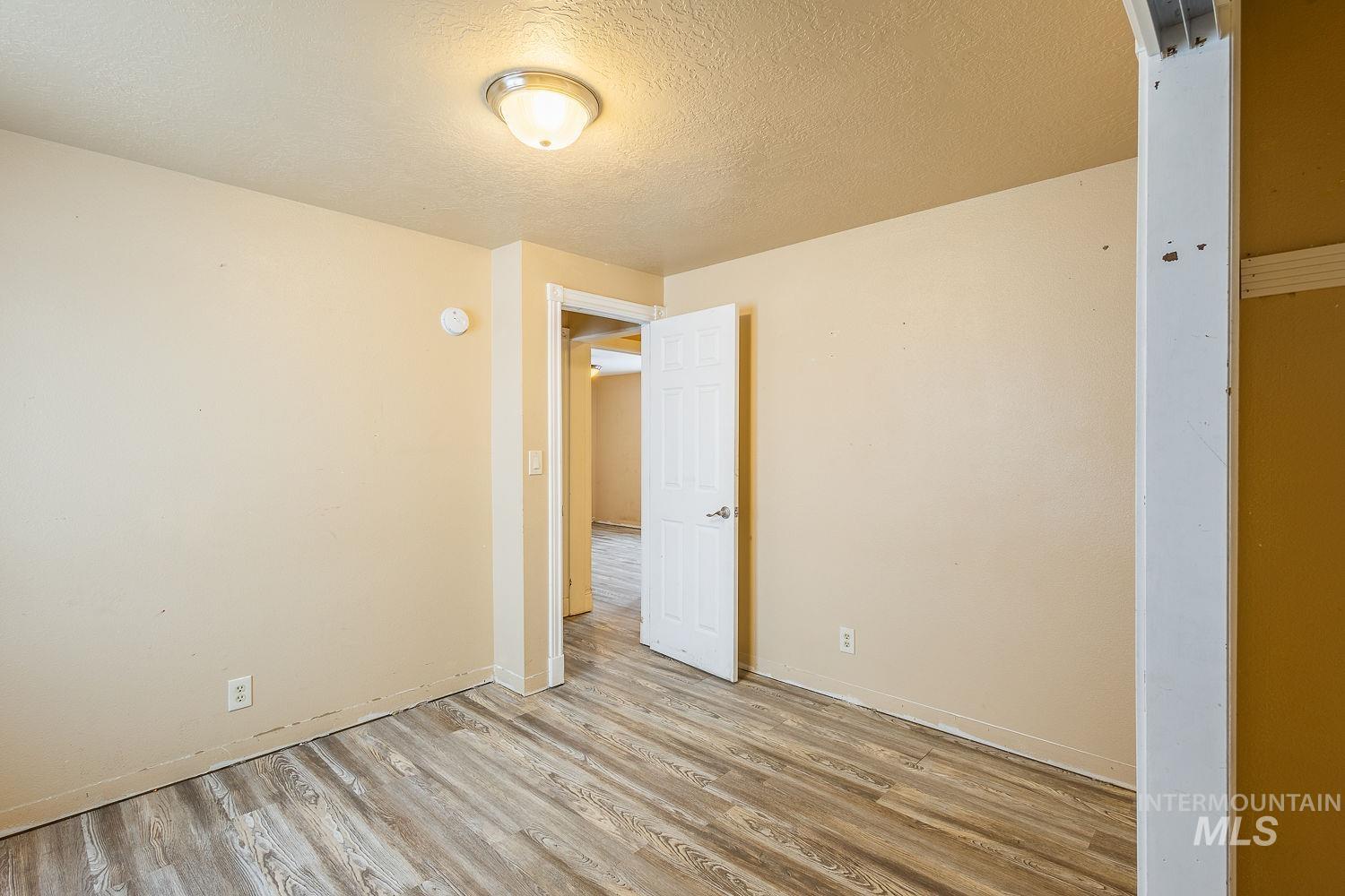 Unfurnished room with a textured ceiling and wood finished floors