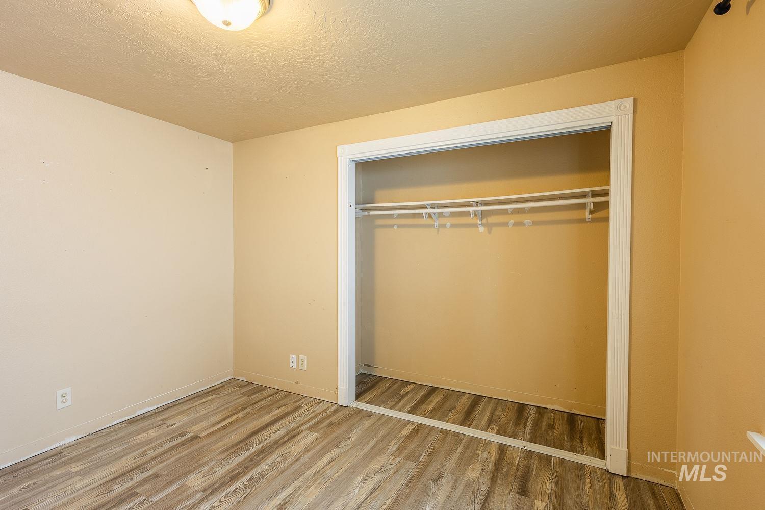 Unfurnished bedroom with a textured ceiling, a closet, and light wood finished floors