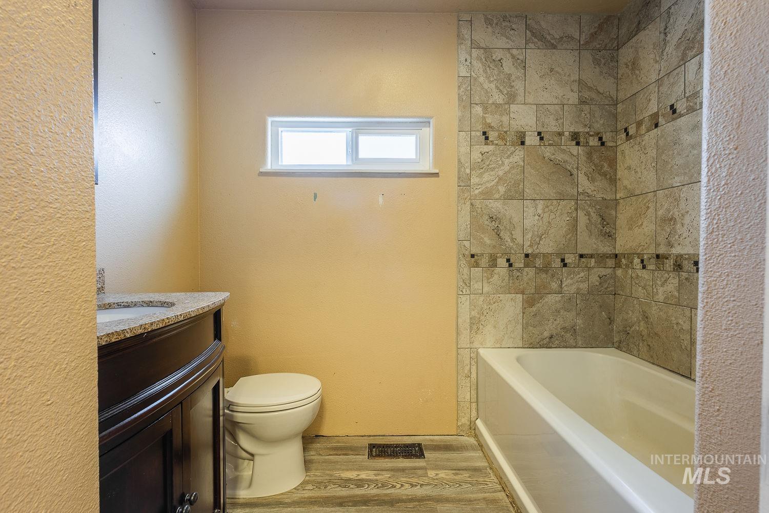 Full bathroom with vanity, light wood-type flooring, and shower / tub combination