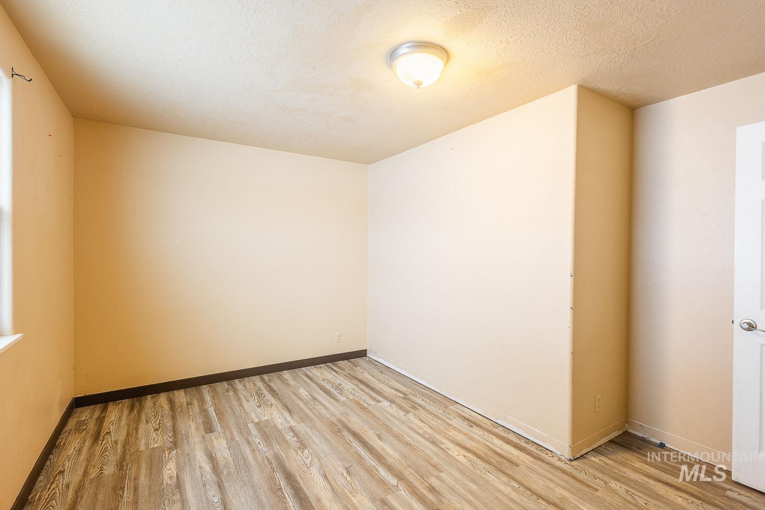 Unfurnished room with a textured ceiling and light wood-style floors