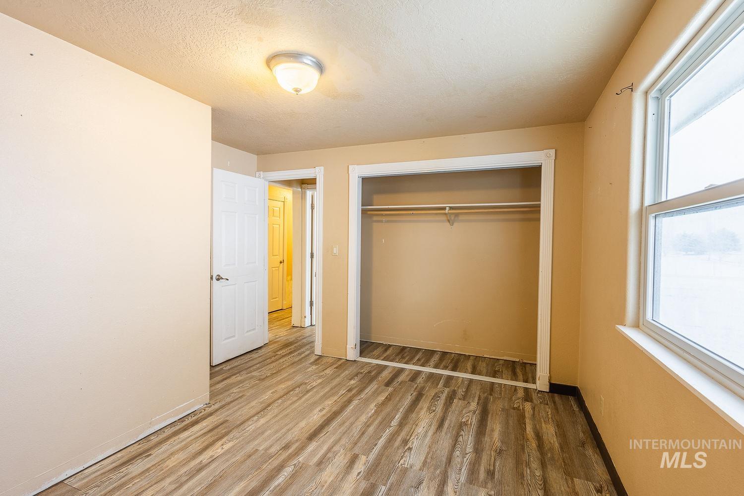 Unfurnished bedroom with a textured ceiling, light wood finished floors, and a closet