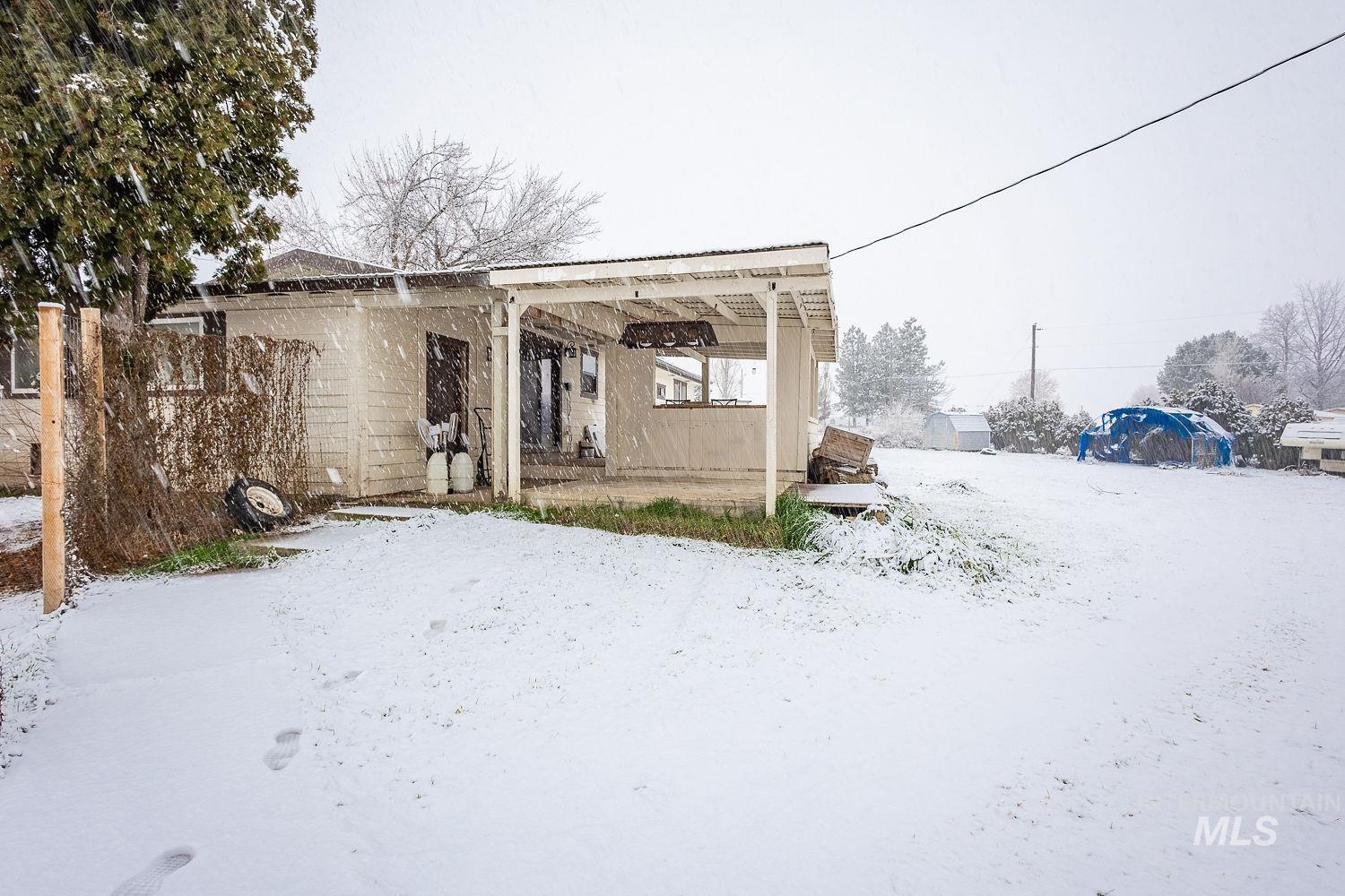 Snow covered back of property featuring a patio