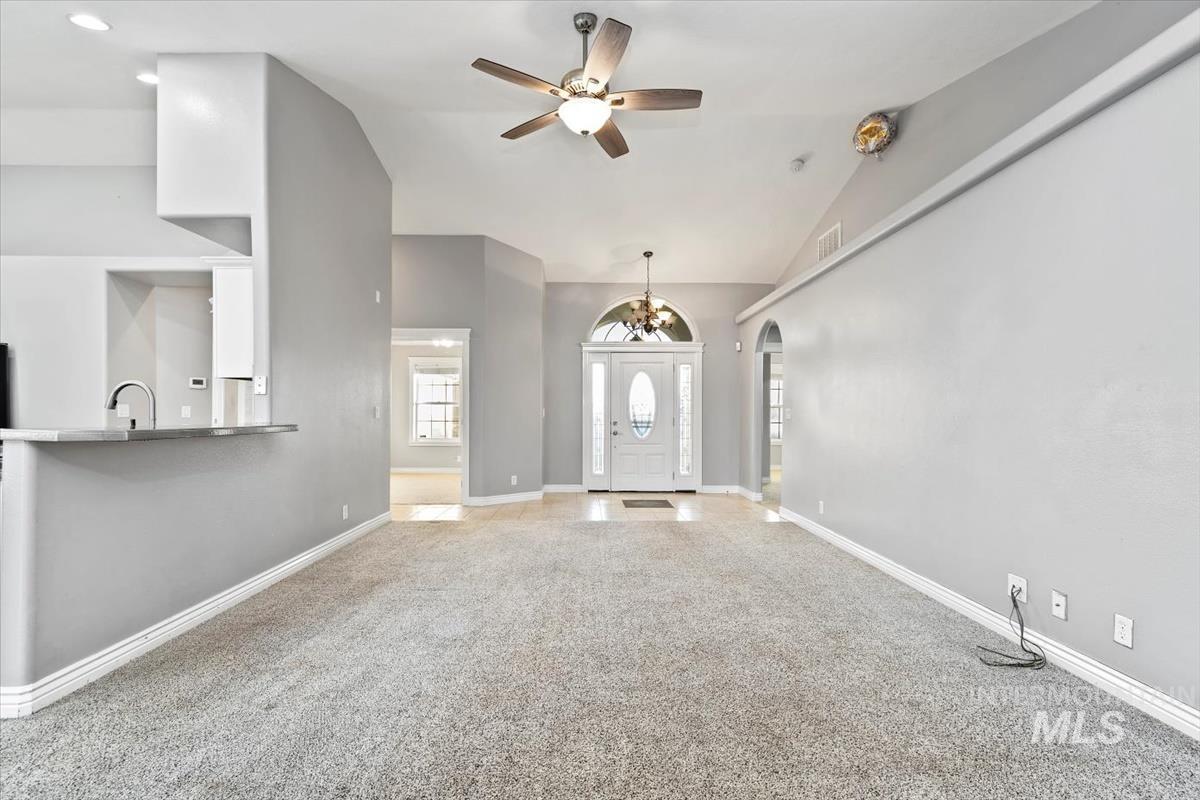 Entryway featuring carpet flooring, lofted ceiling, ceiling fan, a chandelier, and arched walkways