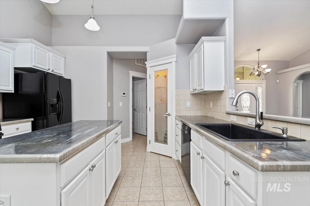 Kitchen featuring hanging light fixtures, a chandelier, white cabinetry, black appliances, and vaulted ceiling