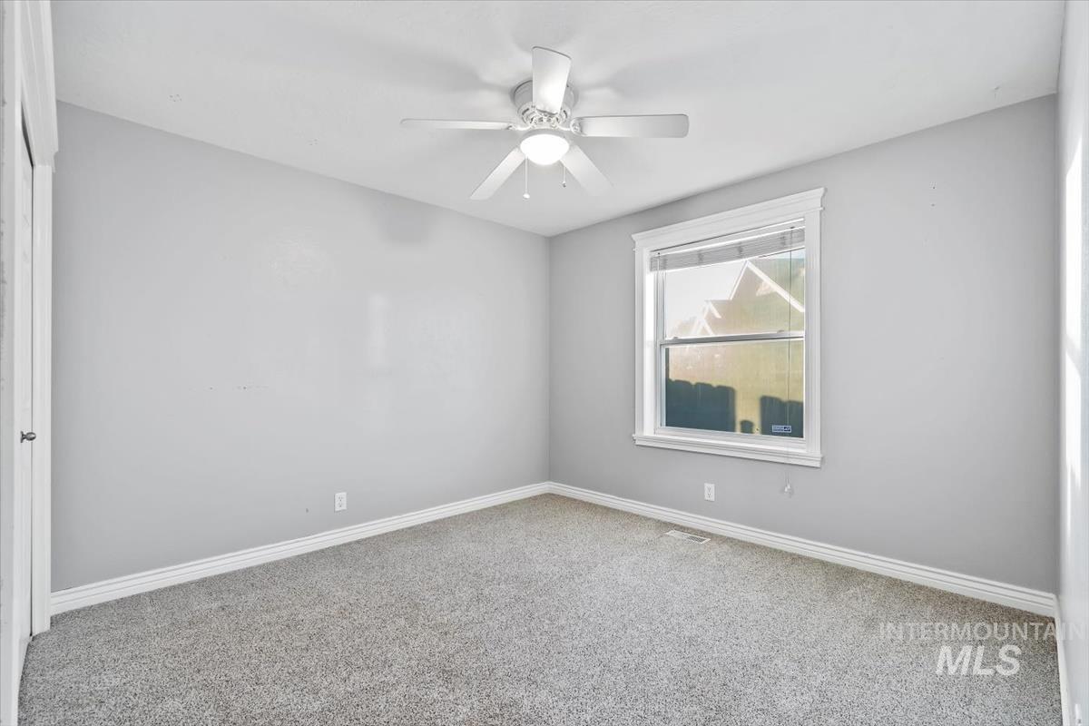 Empty room with carpet floors and a ceiling fan