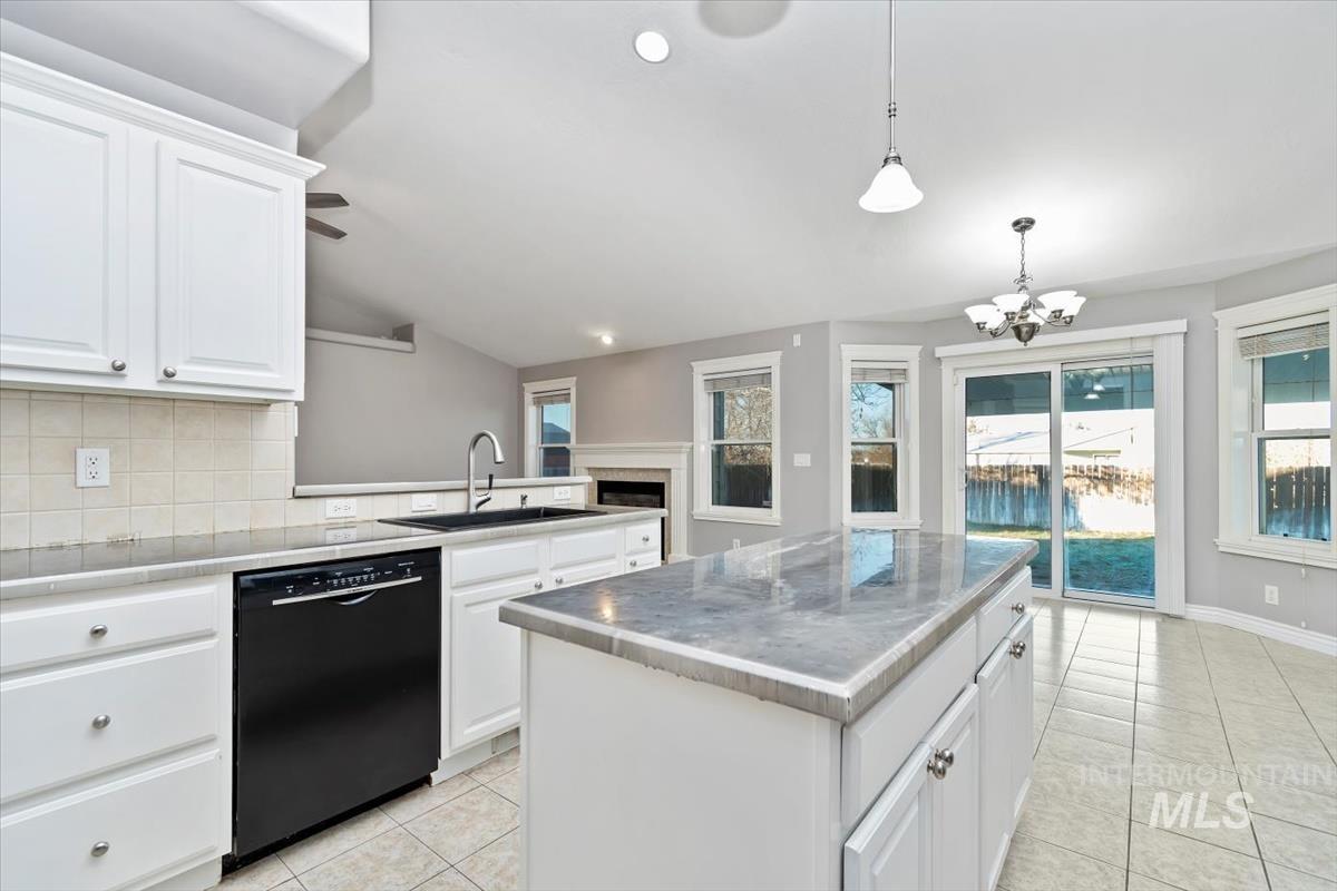 Kitchen with backsplash, white cabinetry, dishwasher, light tile patterned floors, and a kitchen island