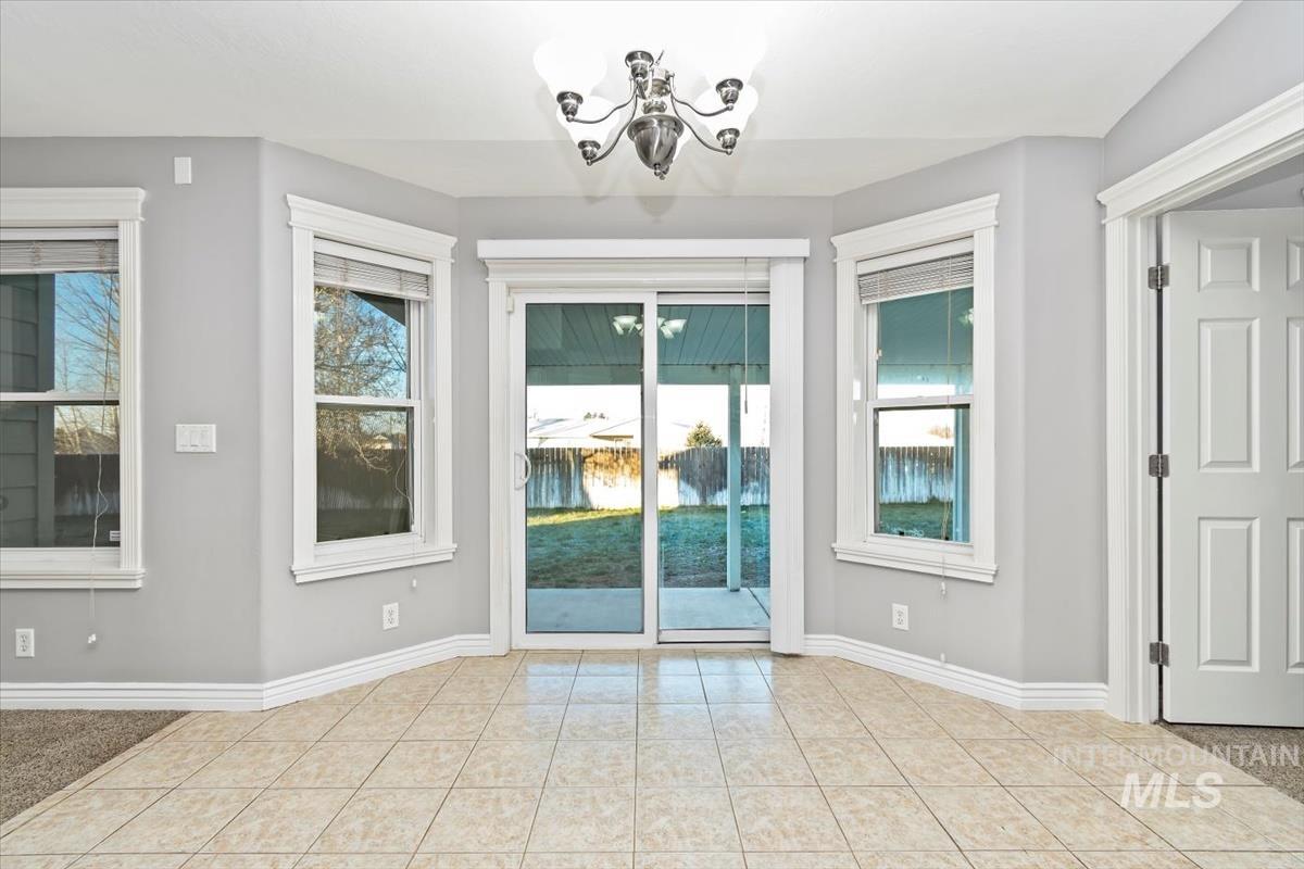 Unfurnished dining area featuring a chandelier, healthy amount of natural light, and light tile patterned floors