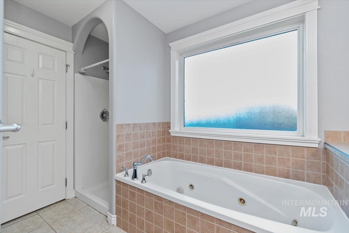 Bathroom featuring a whirlpool tub, a shower stall, and light tile patterned floors