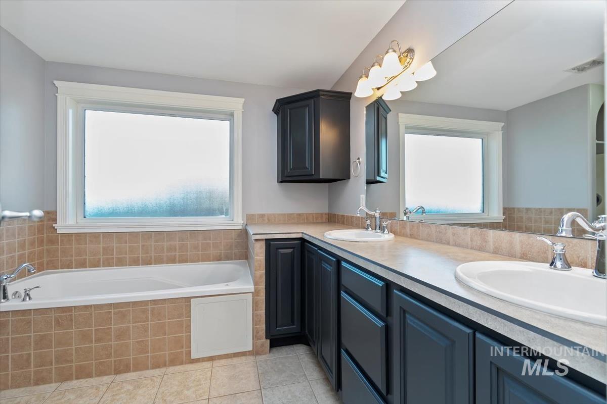 Full bathroom with double vanity, a bath, and light tile patterned flooring