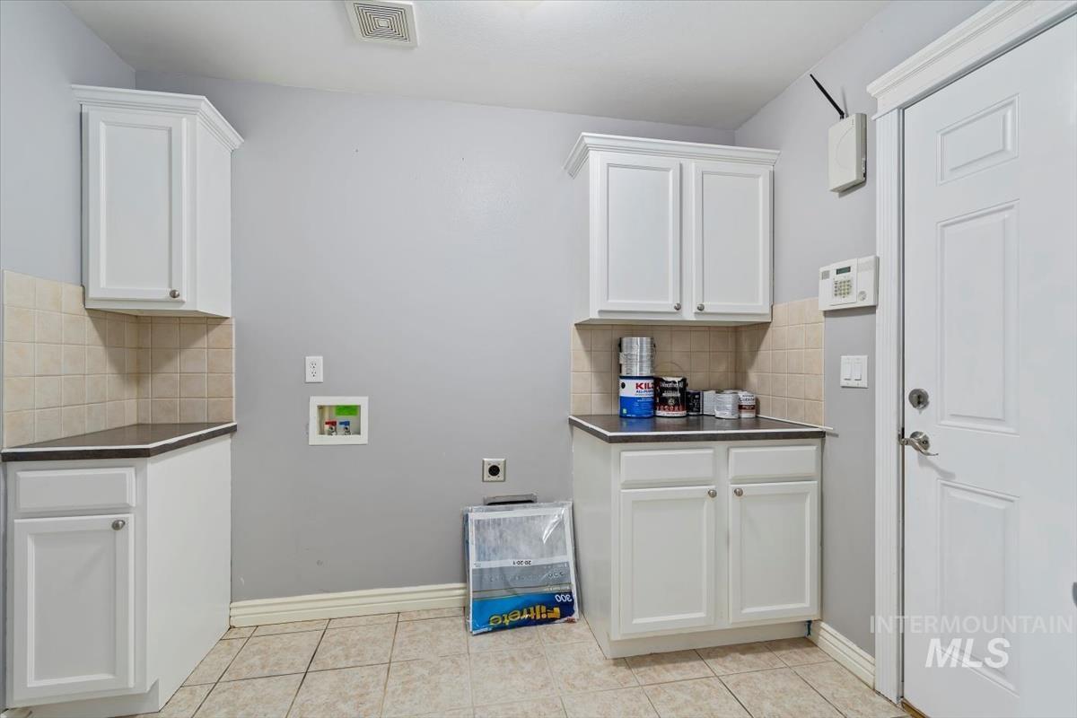 Laundry room with washer hookup, cabinet space, light tile patterned flooring, and electric dryer hookup