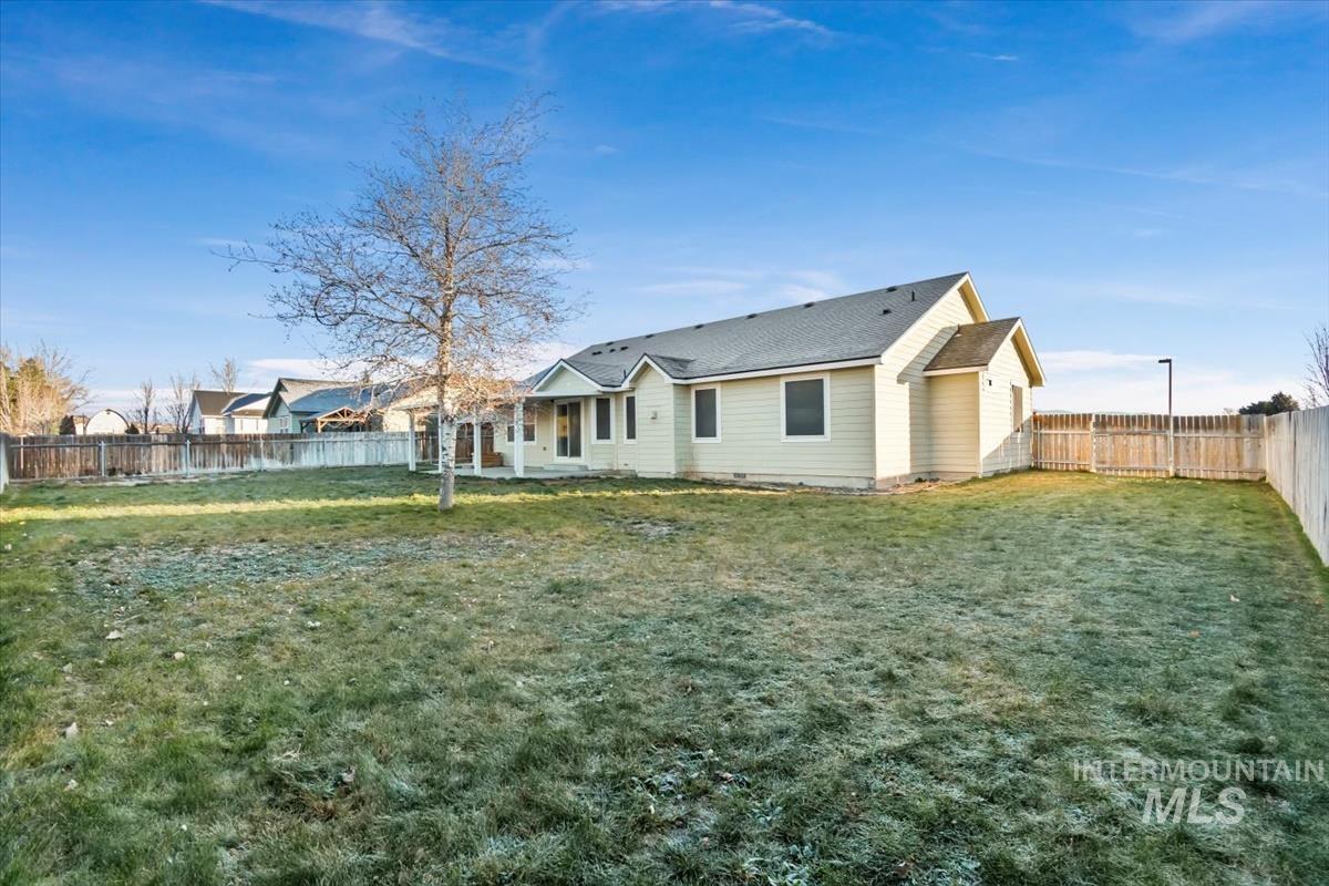 Back of house with a fenced backyard, a patio area, and roof with shingles