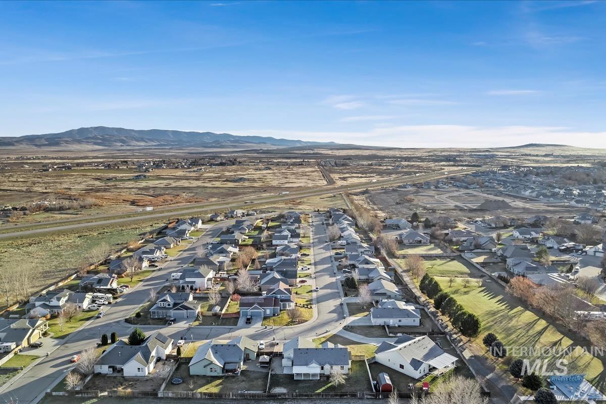 Aerial view of property and surrounding area featuring nearby suburban area and a mountain backdrop