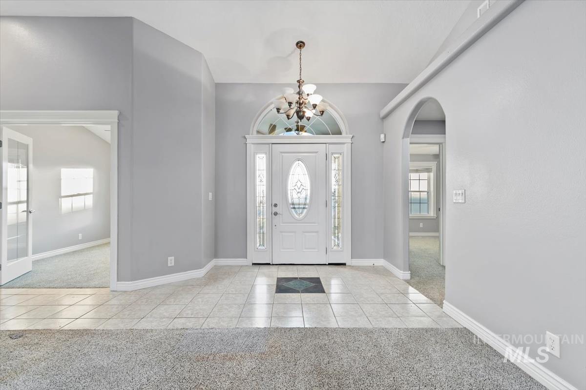 Entrance foyer featuring light colored carpet, light tile patterned floors, and plenty of natural light