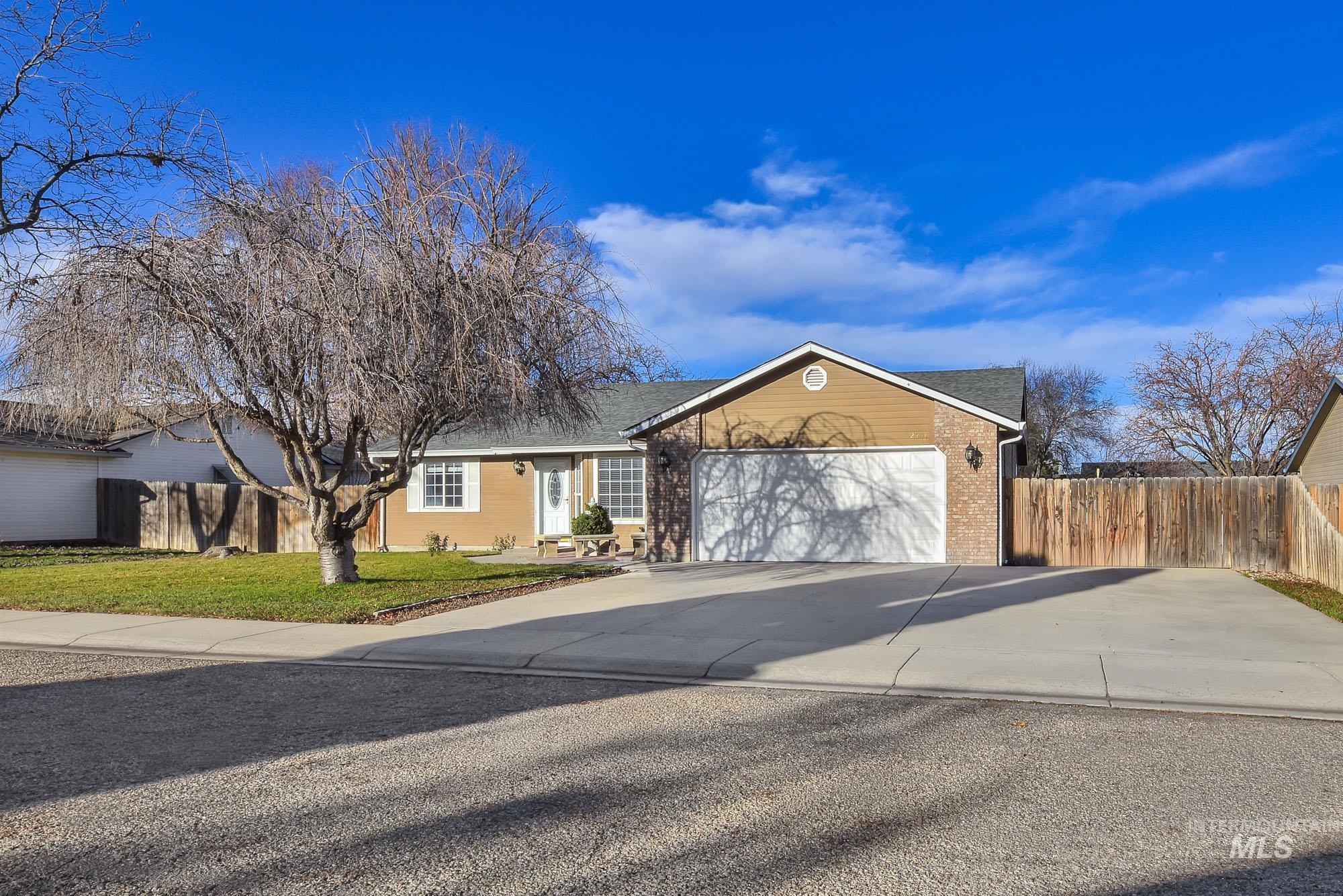 Ranch-style house with concrete driveway, brick siding, an attached garage, and roof with shingles