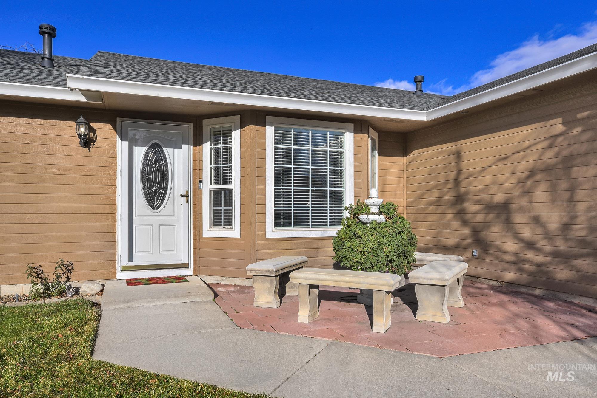 View of exterior entry featuring a patio and a shingled roof